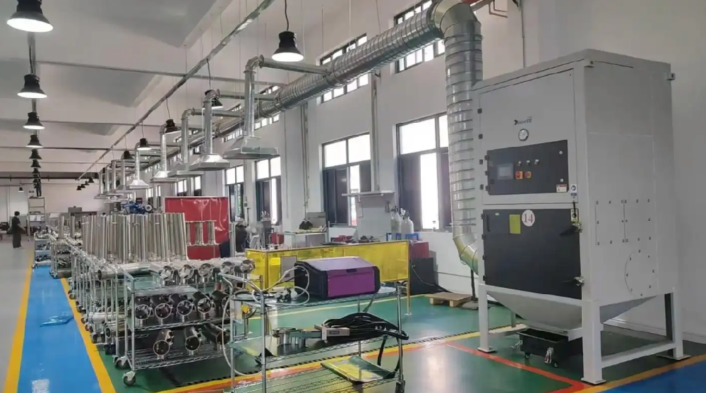工人操作小型布袋除塵器進(jìn)行焊接煙塵收集的車間實(shí)景